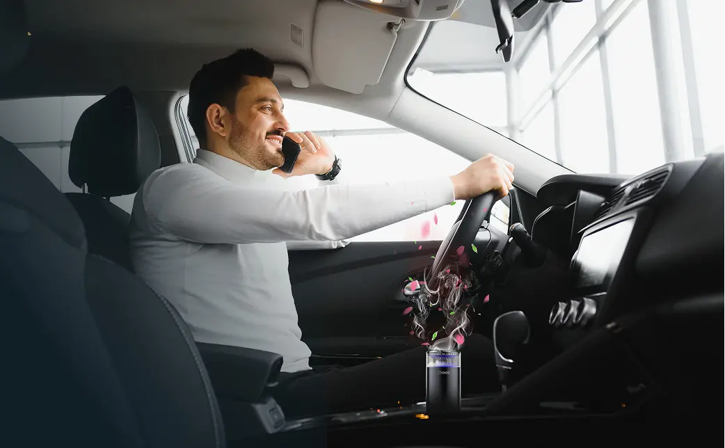 A happy person in a car with the qioob's car perfume diffuser
